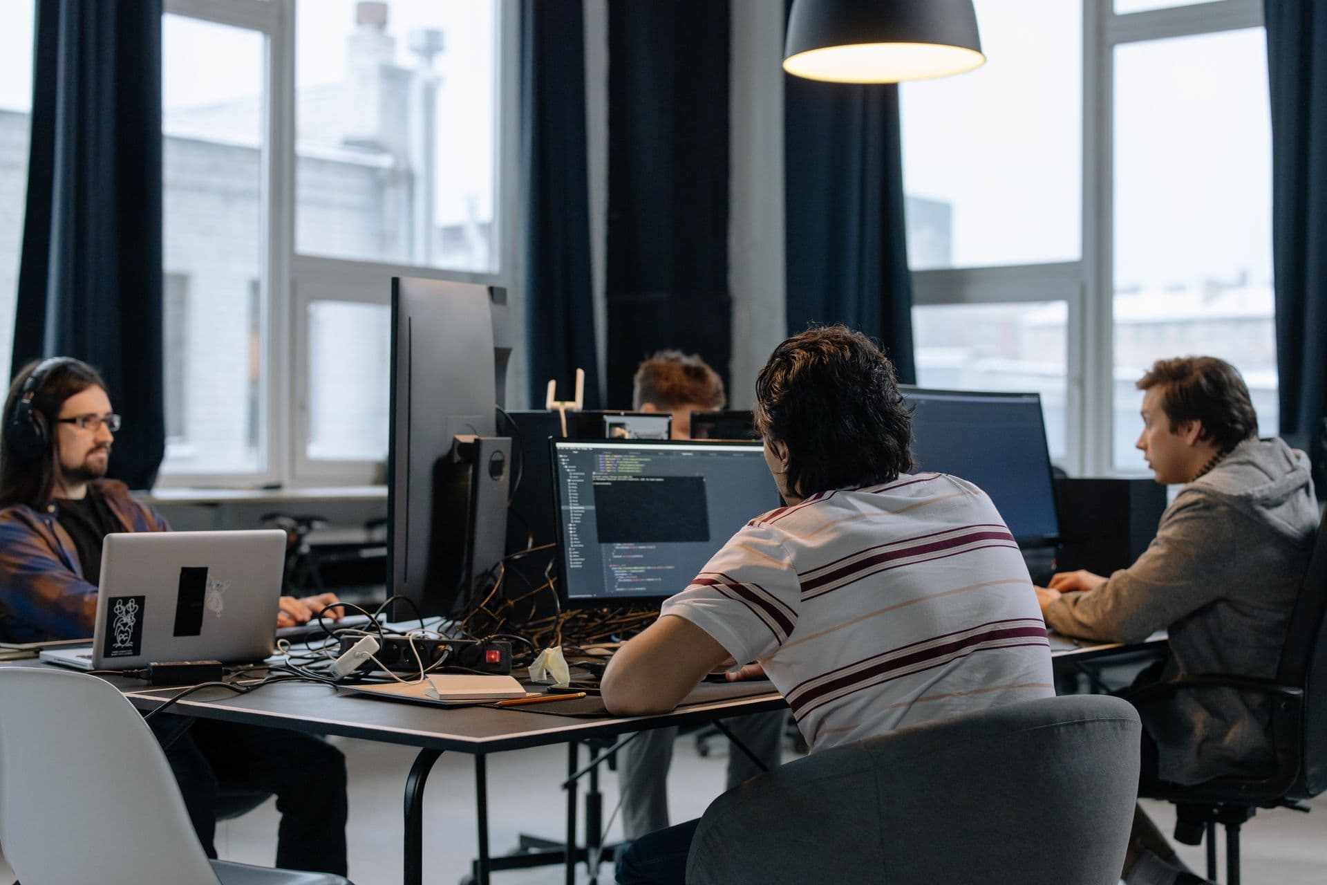Software developers collaborating with AI-assisted coding tools on multiple screens